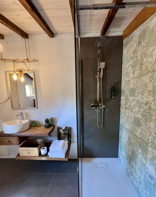 Salle de bain moderne avec douche pluie, lavabo vasque rond, poutres en bois et carrelage décoratif à l'Agritusmo Stecadò