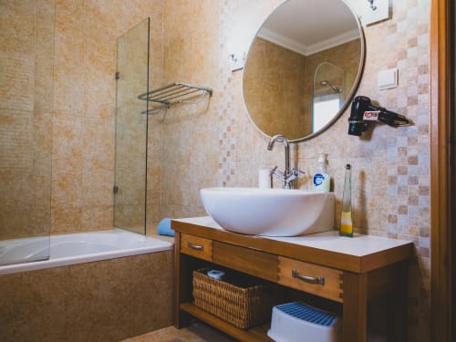 Banheiro moderno com cuba redonda, espelho circular, box de vidro e bancada em madeira na villa Fabulous Beach House