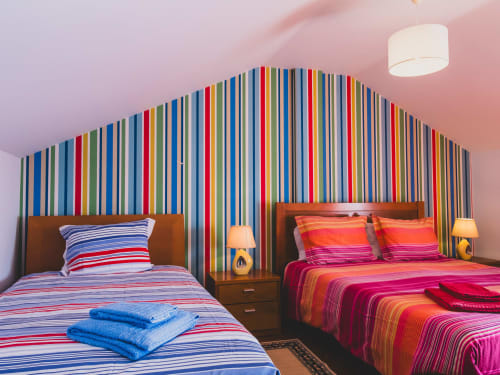 Colorful twin bedroom at Baleal Beach Holiday Villa with striped headboard and matching bedding, wooden nightstands, pink