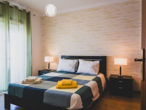 Modern bedroom at Baleal Beach Holiday Villa with colorful striped bedding, wooden accent wall, and sea view in Óbidos,