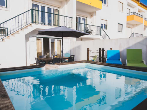 Private pool at Baleal Beach Holiday Villa in Bombarral, Portugal, with lounge seating and white apartment building