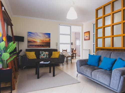 Sala de estar moderna na villa Baleal Sunset Residence em Bombarral com sofás cinzentos, móveis pretos e acentos coloridos