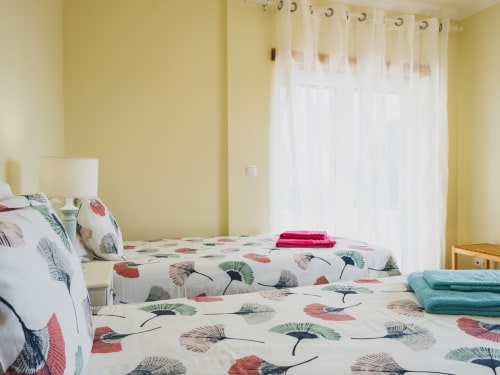 Quarto luminoso na villa Baleal Sunset Residence em Bombarral com camas geminadas, roupa de cama floral e vista para o oceano