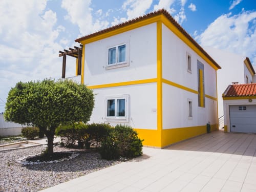 Villa Baleal Sunset Residence em Bombarral com paredes brancas, detalhes amarelos, jardins exuberantes e pátio em Portugal