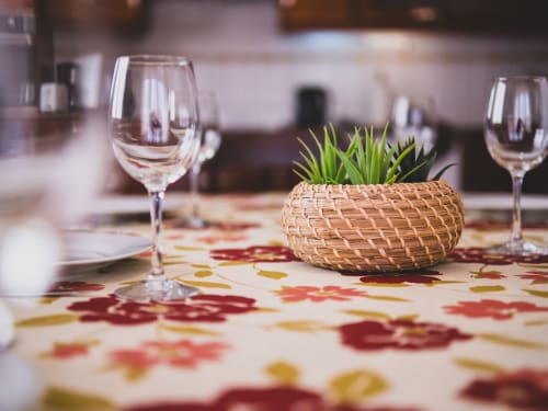 Mesa de jantar elegante com taças de vinho, toalha floral e planta em vaso na villa Baleal Sunset Residence em Bombarral