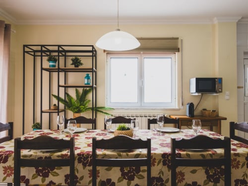 Sala de jantar luminosa na villa Baleal Sunset Residence em Bombarral com cadeiras pretas, luminária branca e plantas em vasos