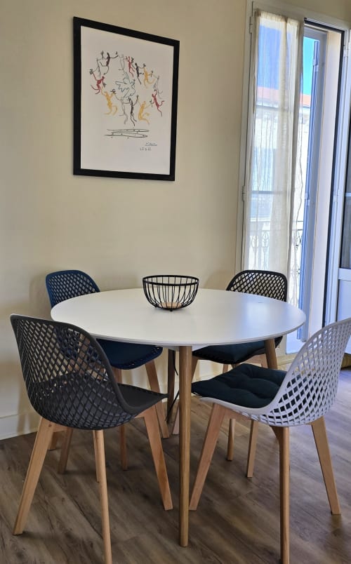 Modern dining room at Hôtel De La Fontaine in Nice with white round table, patterned chairs, and abstract artwork
