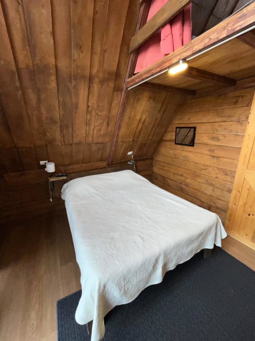 Cozy wooden cabin bedroom with white-covered bed at Chalets Vistas del Poas, Heredia Costa Rica