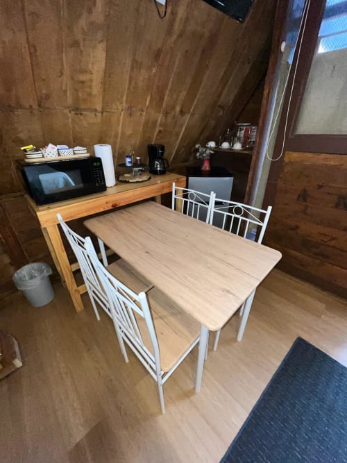 Dining area in Chalet Vistas del Poas villa with wooden table, white chairs, and kitchenette with microwave