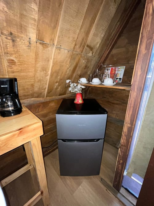 Small kitchenette in Chalets Vistas del Poas villa with wooden walls, black mini-fridge, coffee maker, and shelving with