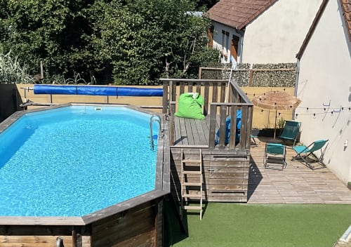 Backyard pool and wooden deck with lounge chairs at Locacharme cottage in Blois, France