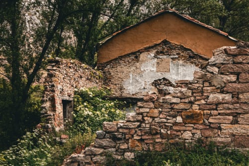 Rústica casa de piedra con tejado de barro rodeada de vegetación en Casa Rural Sensaciones de Cuevas de Viñayo