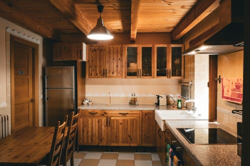 Cocina rústica de madera en la villa Casa Rural Sensaciones de Cuevas de Viñayo con vigas vistas, encimeras de granito y acero inoxidable