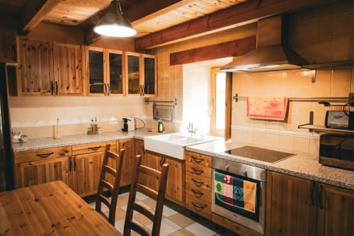 Cocina rústica de madera con fregadero de granja, encimeras de granito y mesa de comedor en la villa Casa Rural Sensaciones