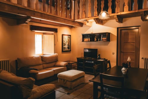 Acogedora sala de estar en villa Casa Rural Sensaciones con paredes de terracota, sofá de cuero, vigas de madera y vistas a la montaña