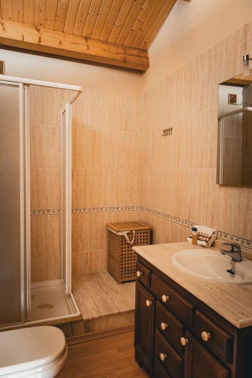Baño moderno con azulejos efecto madera, mueble oscuro y ducha en la villa Casa Rural Sensaciones