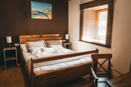 Acogedora cama de madera en dormitorio de villa con vistas a la montaña y obras de arte costero en Casa Rural Sensaciones