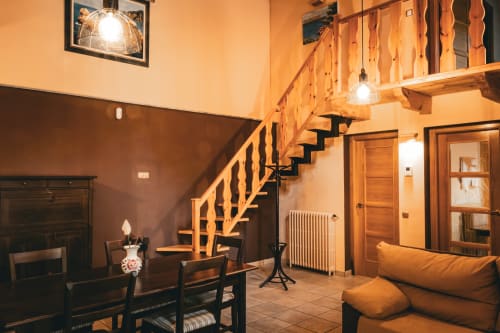 Cálido interior rústico de la villa Casa Rural Sensaciones con escalera de madera, chimenea y acogedora sala de estar en Cuevas de