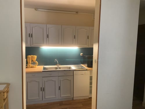 Cuisine moderne de l'appartement Hôtel De La Bonnheur avec armoires blanches, dosseret turquoise et évier en acier inoxydable