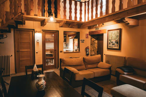 Acogedora sala de estar de Casa Rural Sensaciones con sofá naranja, vigas de madera y encanto rústico de la campiña española en Cuevas de