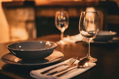 Elegante mesa de comedor formal en Casa Rural Sensaciones con copas de vino, platos oscuros y cubertería