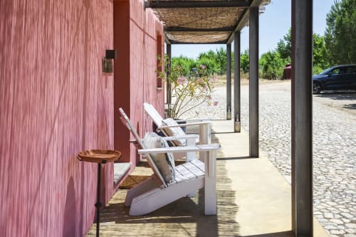 Sillas Adirondack blancas en terraza de madera junto a edificio rosa en Casa das Jardas, retiro rural en Ladoeiro, Portugal