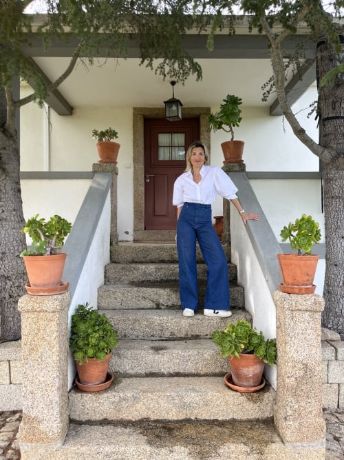 Mulher na entrada da casa rural Casa das Jardas em Ladoeiro, Portugal, com vasos de terracota e degraus de pedra