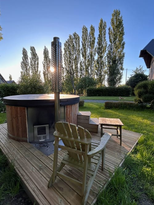 Outdoor hot tub with wooden deck seating at Domaine de Blanvatel B&B in Saint Pierre en Auge, France, surrounded by poplar