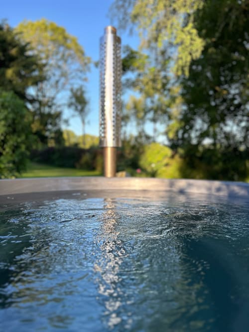 Water feature at Domaine de Blanvatel B&B in Saint Pierre en Auge with tall metallic sculpture and garden trees