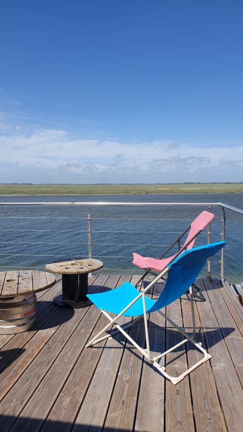 Chaises longues colorées sur terrasse en bois avec vue sur la baie de Somme, gîte Vue D'ici, Saint Valery sur Somme