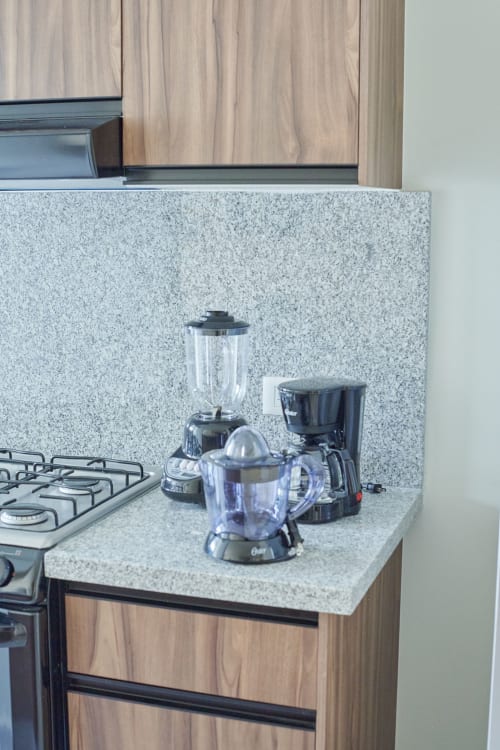 Moderna encimera de cocina en departamento Pares Homes CDMX con licuadora, extractor de jugos, cafetera y estufa de gas