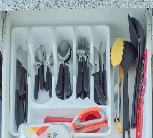 Cajón de cocina organizado en apartamento Pares Homes CDMX con utensilios, cubiertos y herramientas de servicio coloridas en divisores.