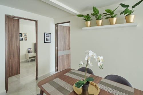 Comedor de departamento moderno en Pares Homes Ciudad de México con orquídea blanca, plantas en maceta, puertas de madera y diseño contemporáneo