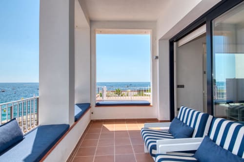 Beachfront apartment terrace in Palafrugell with sea views, striped loungers, and direct beach access