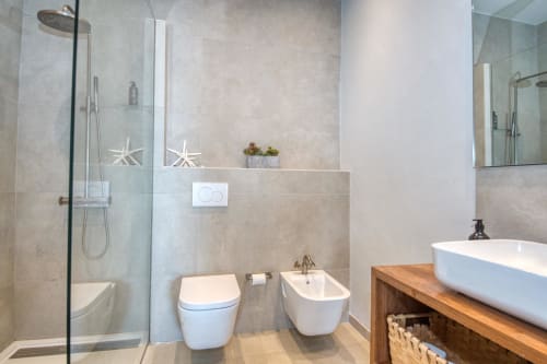 Modern bathroom with walk-in shower, toilet, bidet, and vessel sink in coastal Palafrugell apartment