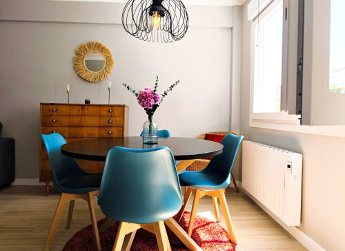 Comedor moderno en apartamento Holibai, Baiona con sillas azules, mesa redonda y aparador de madera