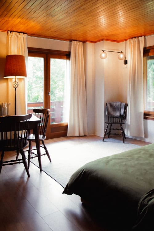 Vue de l'intérieur de la chambre : bureau, chaises vintage, lit et lumières cosy