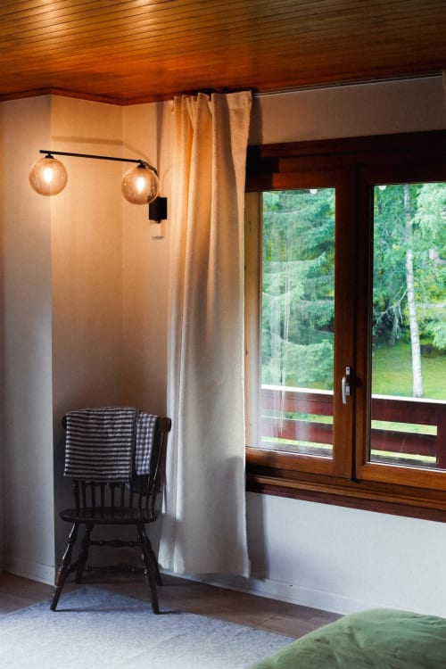 Vue de l'intérieur de la chambre : chaises vintage, lit et lumières cosy