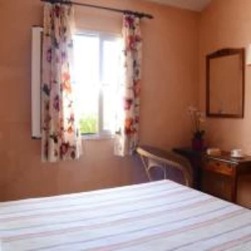 Amplia habitación de villa en Las Golondrinas con paredes de terracota, cortinas florales, ventana con vista a la piscina y muebles de madera