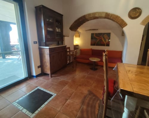 Rustikaler Lounge-Bereich im Agri-Bio Santa Palmira Hotel in Pomarance mit Terrakottaboden, rotem Sofa und Gewölbedecke