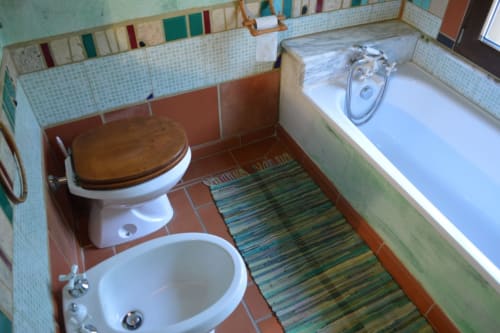 Farbiges Badezimmer im Agri-Bio Santa Palmira mit Toilette, Waschbecken, Badewanne und gestreifter Badematte in Pomarance