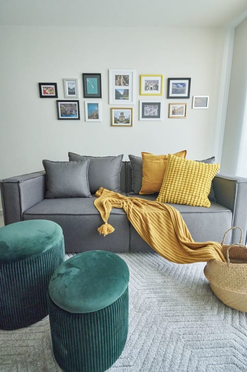Sala moderna en departamento Pares Homes CDMX con sofá gris, acentos amarillos, puffs color teal y galería de cuadros