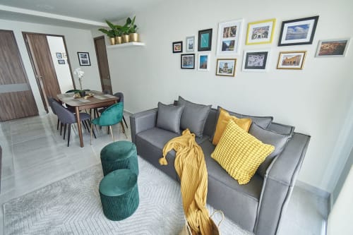 Apartamento moderno en CDMX en Pares Homes con sofá gris, acentos amarillos, mesa de comedor y galería de fotos enmarcadas