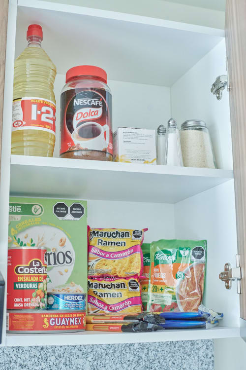 Estante de alacena en departamento Pares Homes CDMX con aceites de cocina, café, arroz, fideos ramen y conservas