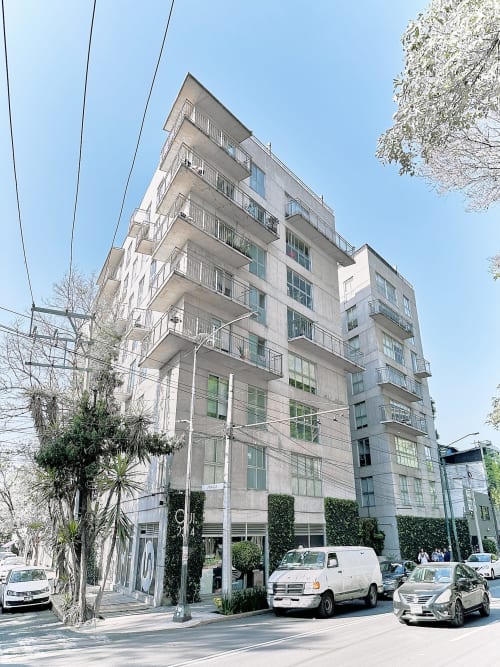 Edificio de apartamentos moderno en la Ciudad de México con vista de calle, autos estacionados y cielo despejado