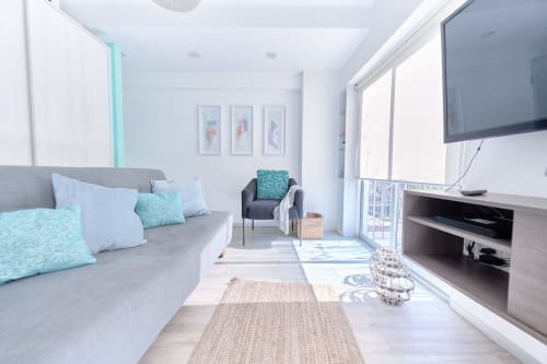 Moderno departamento en CDMX de Pares Homes con acentos turquesas, sofá gris, vista de la ciudad, TV de pantalla plana y amplia luz natural