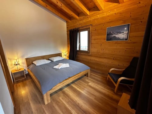 Chambre douillette en bois à La Tzoumaz avec lit double, vue montagne et décor alpin