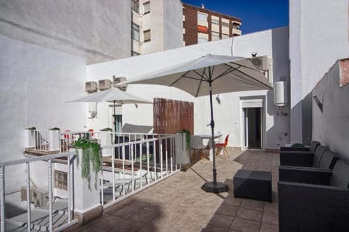 Terraza en azotea del apartamento Gestyp-AT en Mérida con sombrillas, asientos y vistas de la ciudad