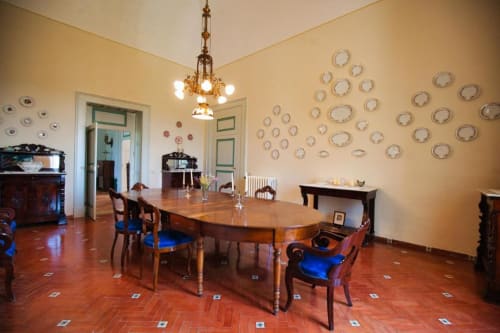 Elegante sala da pranzo di Villa Ceci ad Andria con tavolo in legno, piatti decorativi su pareti gialle, pavimenti in cotto