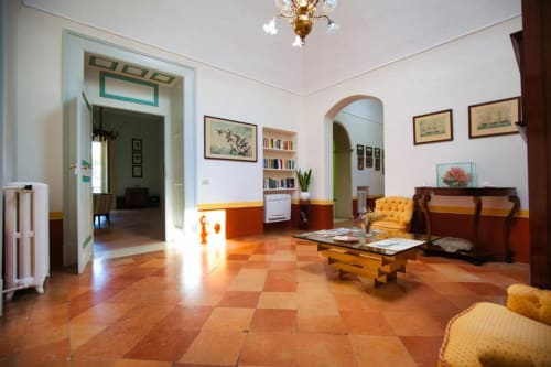 Ampio soggiorno di Villa Ceci B&B ad Andria con pavimenti in terracotta, poltrona gialla e ingresso ad arco